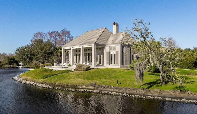 back of property with a water view and a yard