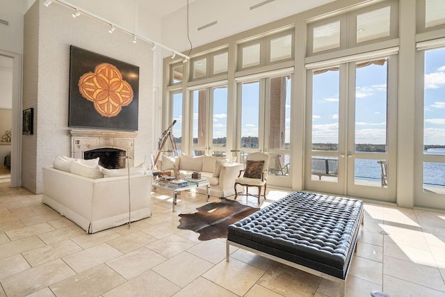 sunroom / solarium featuring french doors, a water view, and rail lighting