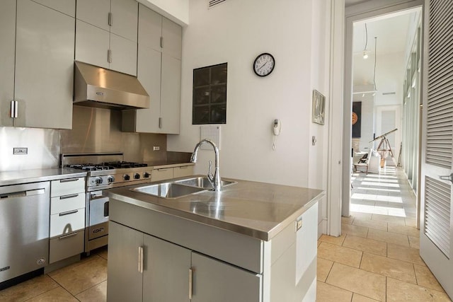 kitchen with backsplash, sink, light tile patterned floors, an island with sink, and stainless steel appliances