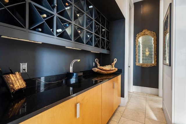 bar with dark stone countertops and light tile patterned floors