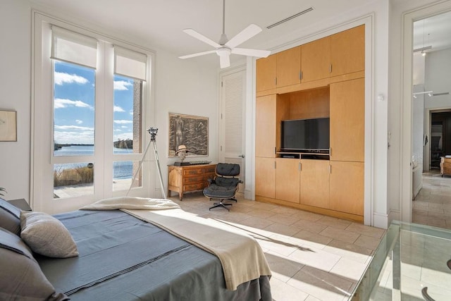 bedroom featuring ceiling fan, a water view, and light tile patterned flooring