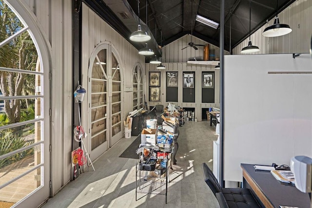 home office with ceiling fan, wooden walls, and high vaulted ceiling