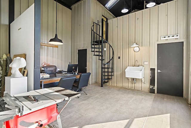 home office featuring wooden walls, sink, and high vaulted ceiling