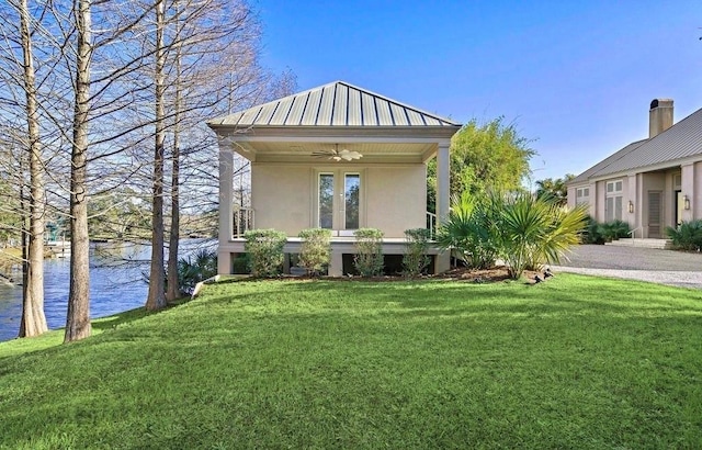 view of front of house with a water view, ceiling fan, and a front lawn