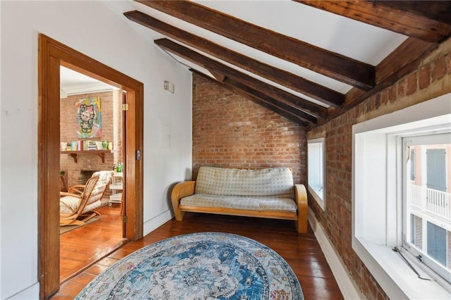 living area with hardwood / wood-style floors, lofted ceiling with beams, and brick wall