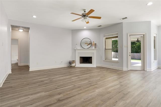 unfurnished living room with ceiling fan and wood-type flooring