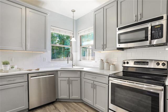 kitchen with a sink, stainless steel appliances, gray cabinets, and decorative backsplash