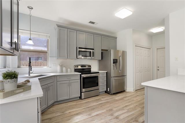 kitchen featuring stainless steel appliances, gray cabinets, a sink, and light wood finished floors