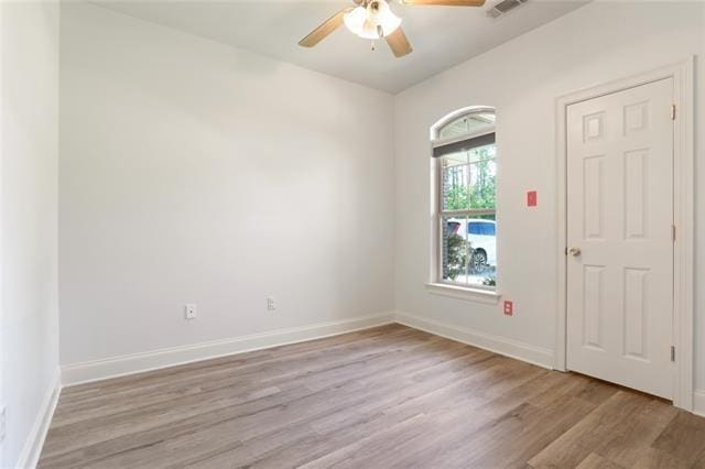 spare room with ceiling fan, light wood-style flooring, visible vents, and baseboards