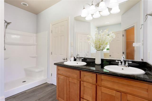 bathroom with a shower, wood finished floors, a sink, and double vanity