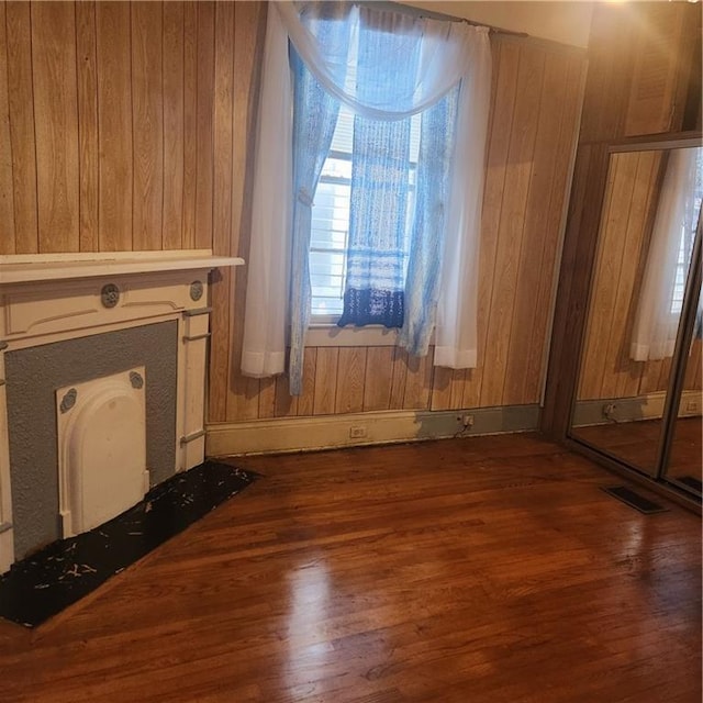 unfurnished living room featuring wood walls and dark wood-type flooring