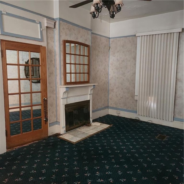 unfurnished living room with a tile fireplace, carpet floors, and ceiling fan