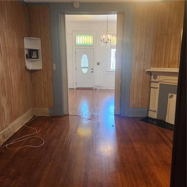 entrance foyer featuring wood walls, a chandelier, and dark hardwood / wood-style floors