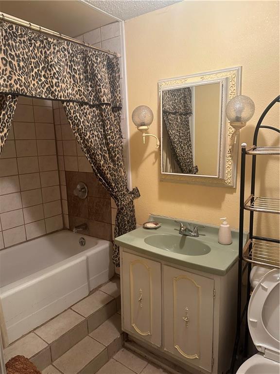 bathroom featuring tile patterned floors, shower / tub combo, vanity, and a textured ceiling