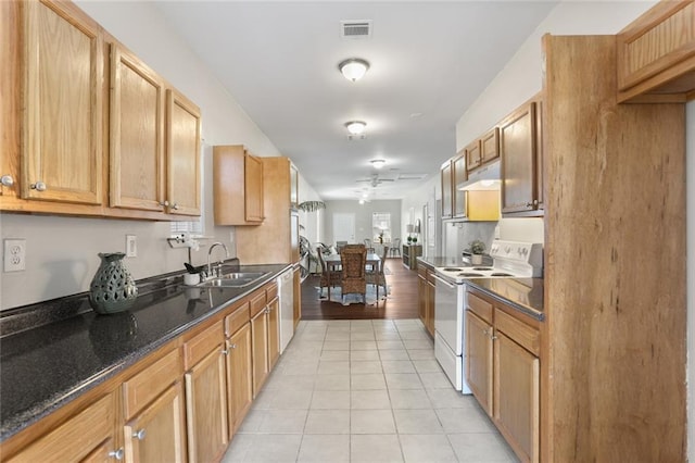 kitchen with light tile patterned floors, dark stone counters, sink, and white appliances