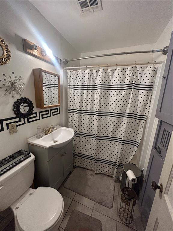 bathroom with tile patterned flooring, a shower with curtain, vanity, and toilet