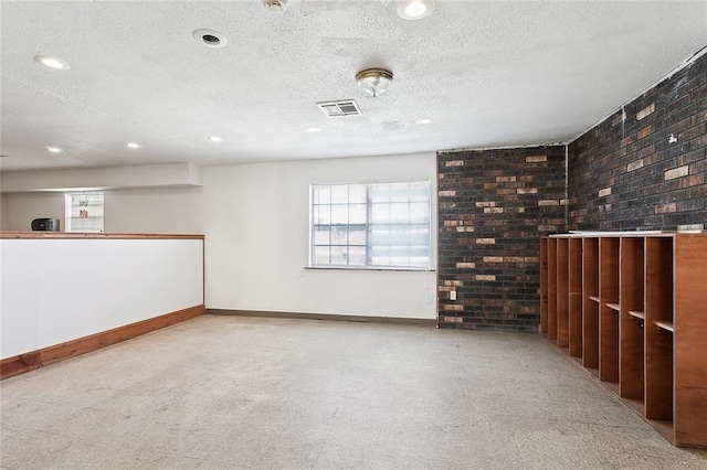 interior space with a textured ceiling and brick wall