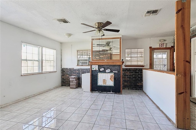 unfurnished living room featuring ceiling fan, brick wall, cooling unit, a textured ceiling, and light tile patterned floors