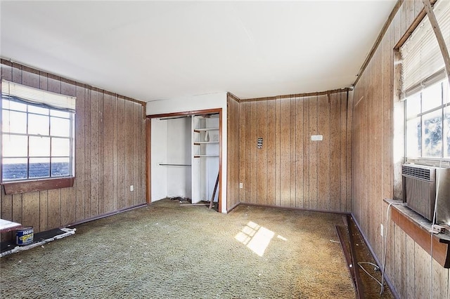 unfurnished bedroom with dark carpet, a closet, cooling unit, and wood walls