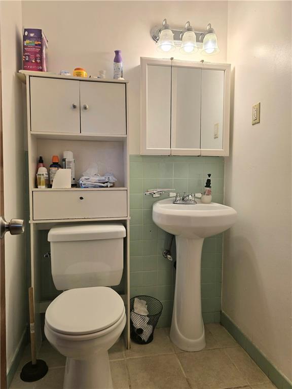 bathroom with sink, tile patterned flooring, tile walls, and toilet