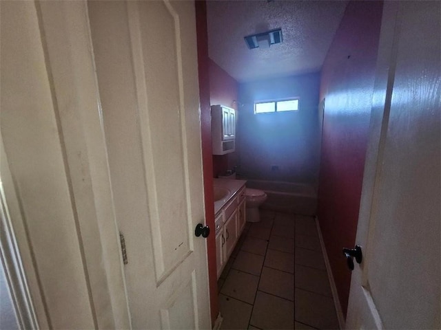 bathroom with tile patterned floors, vanity, toilet, and a textured ceiling