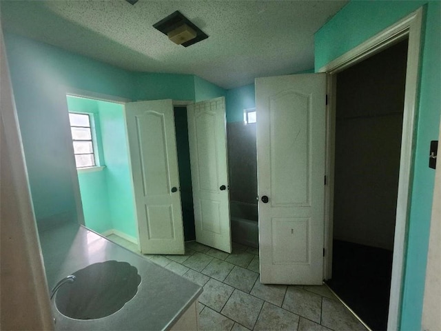 bathroom with a textured ceiling and a tub to relax in