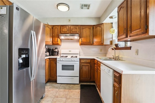 kitchen featuring decorative light fixtures, white appliances, sink, and light tile patterned floors