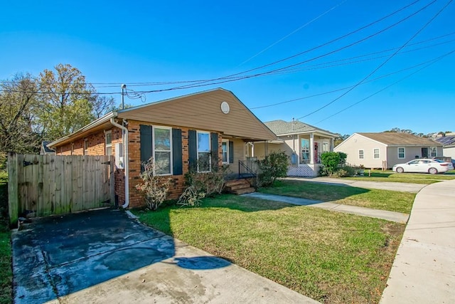 view of front facade with brick siding, a residential view, covered porch, fence, and a front yard