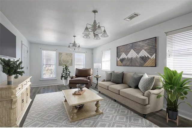 living area featuring baseboards, visible vents, a notable chandelier, and wood finished floors