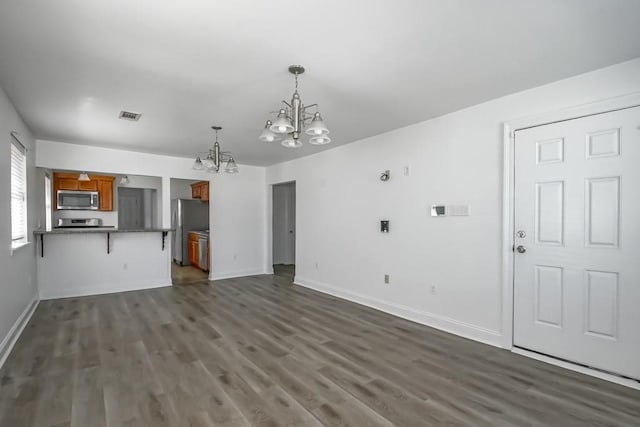 unfurnished living room featuring baseboards, visible vents, a chandelier, and dark wood-type flooring