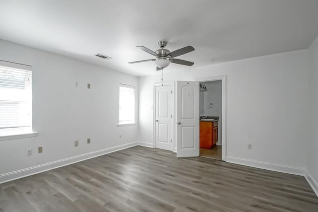 unfurnished bedroom featuring baseboards, visible vents, dark wood finished floors, and connected bathroom