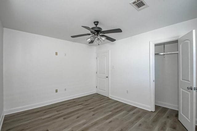 unfurnished bedroom with baseboards, a closet, visible vents, and dark wood-type flooring