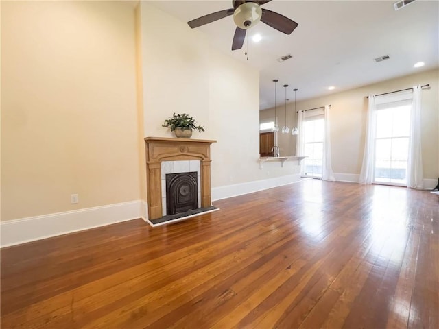 unfurnished living room with a fireplace, dark hardwood / wood-style flooring, and ceiling fan