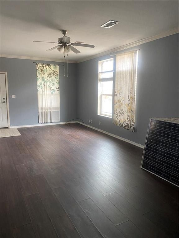 spare room featuring a ceiling fan, dark wood-style flooring, ornamental molding, and visible vents