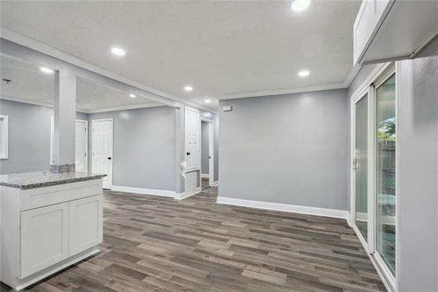 interior space with light stone countertops, crown molding, white cabinets, and dark wood-type flooring