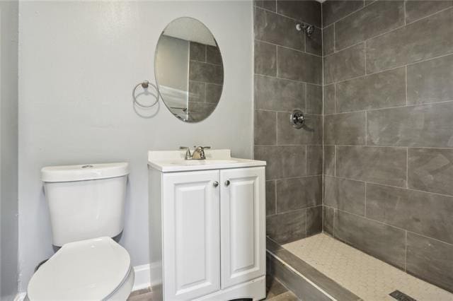 bathroom with tiled shower, vanity, and toilet