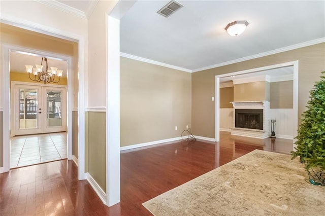 interior space featuring a fireplace, ornamental molding, dark hardwood / wood-style flooring, french doors, and a chandelier