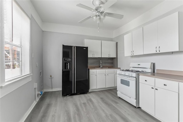 kitchen with ceiling fan, black refrigerator with ice dispenser, light hardwood / wood-style flooring, white range with gas cooktop, and white cabinets