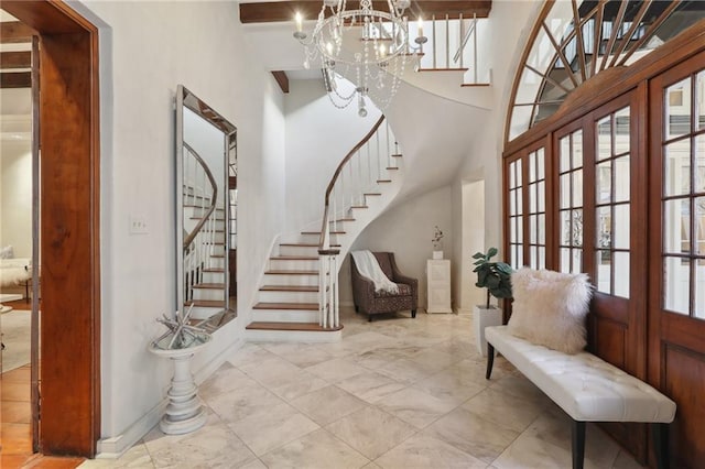 entrance foyer featuring french doors, a notable chandelier, and beam ceiling