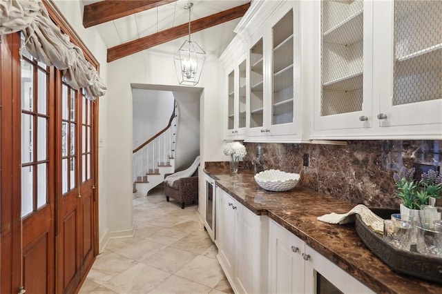 kitchen featuring white cabinets, hanging light fixtures, vaulted ceiling with beams, dark stone countertops, and tasteful backsplash