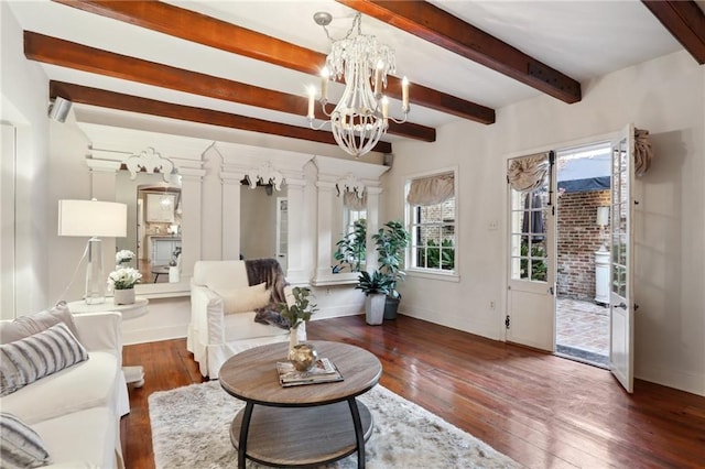 living room featuring beamed ceiling, dark hardwood / wood-style floors, ornate columns, and an inviting chandelier