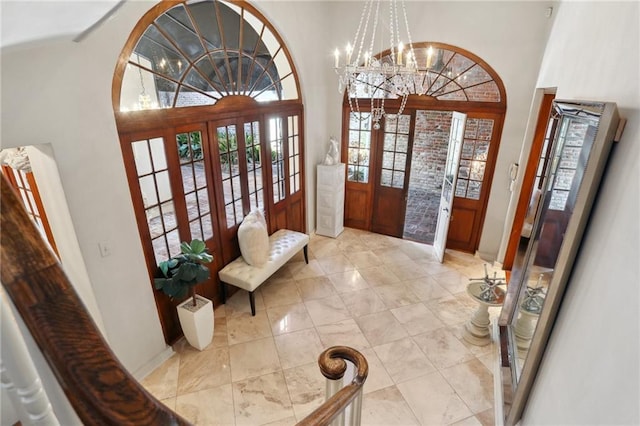 interior space with a notable chandelier, a towering ceiling, and french doors