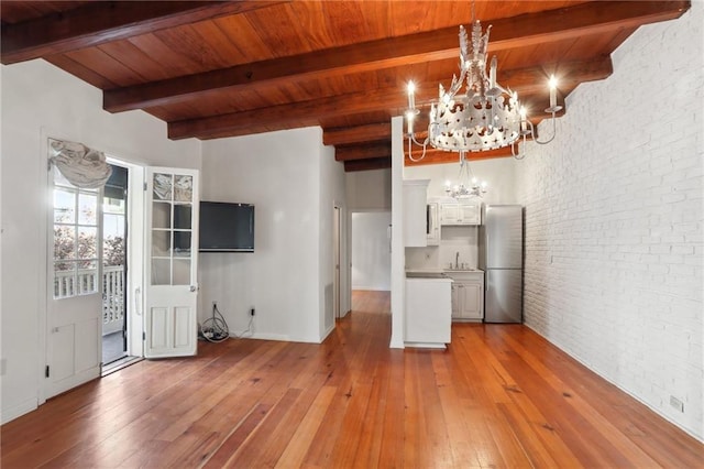 kitchen with white cabinets, decorative light fixtures, stainless steel refrigerator, and brick wall