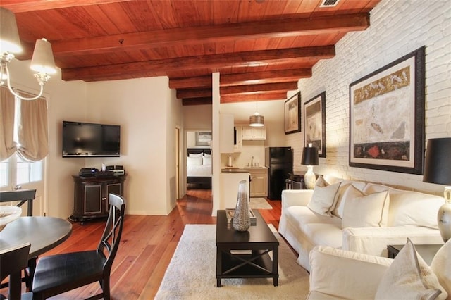 living room with beamed ceiling, sink, light hardwood / wood-style floors, and brick wall