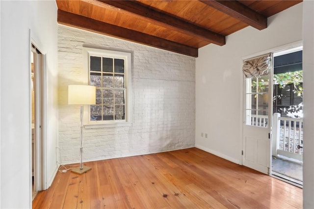 empty room with beamed ceiling, wooden ceiling, brick wall, and light wood-type flooring