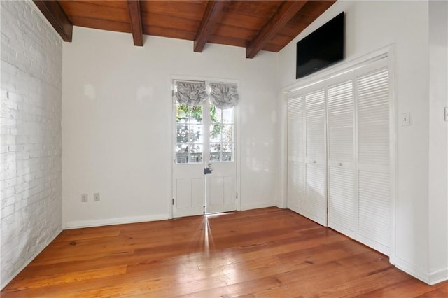 unfurnished bedroom with vaulted ceiling with beams, hardwood / wood-style floors, and wooden ceiling