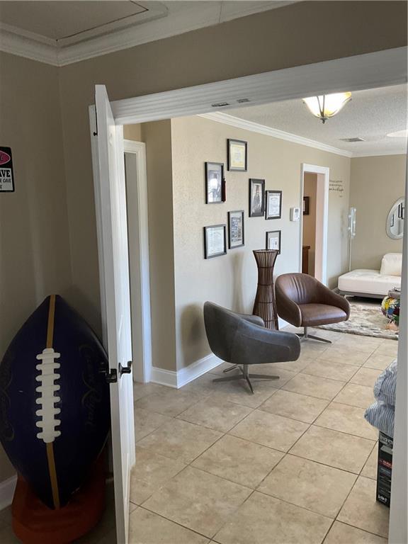 living area featuring light tile patterned floors and crown molding