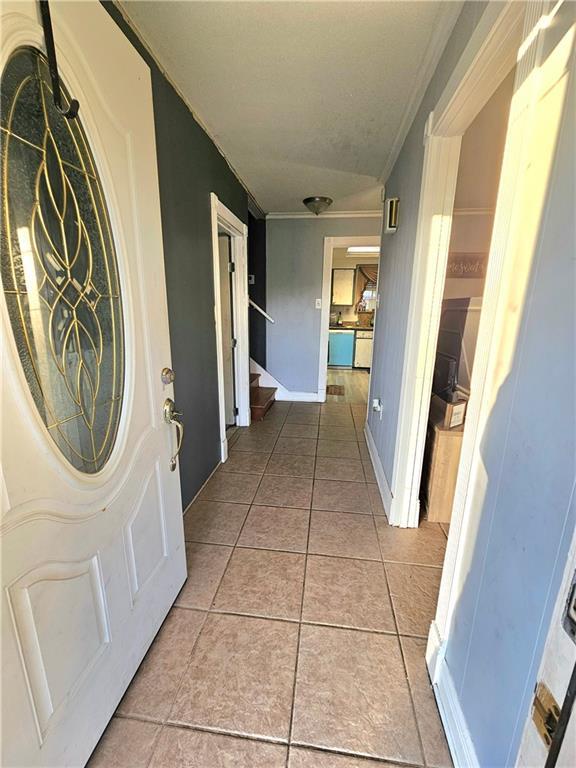 corridor featuring crown molding and light tile patterned flooring