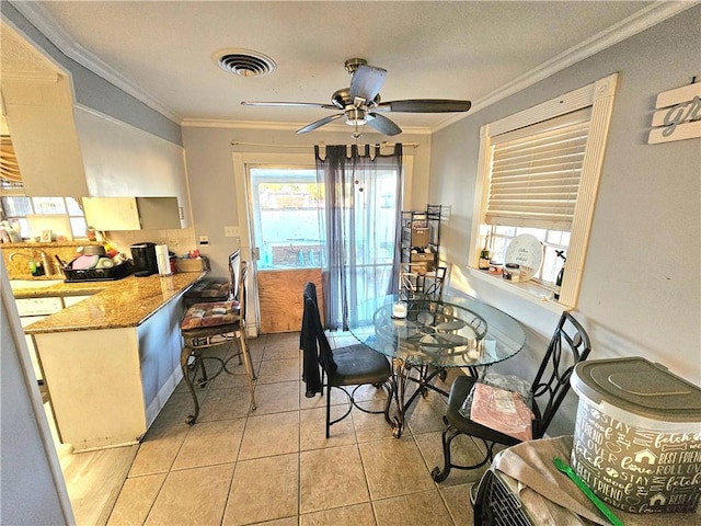 tiled dining space with ornamental molding and ceiling fan