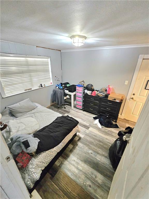 bedroom with hardwood / wood-style floors, crown molding, and a textured ceiling